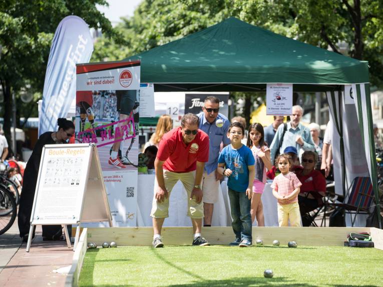Ein Junge und sein älterer Begleiter beim Boule spielen